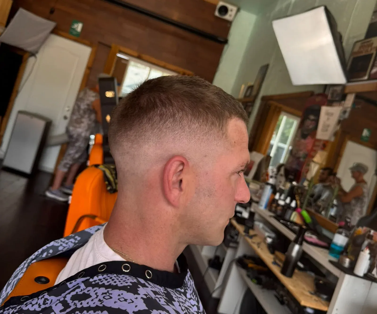 A finished skin fade in the Amit Blends chair, with the shop's mirror and tools behind.
